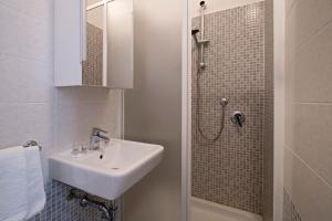 a white bathroom with a sink and a shower at Hotel Torre in Viareggio