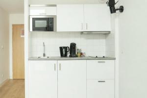 a white kitchen with white cabinets and a microwave at Les Lilas Serviced Apartments in Les Lilas