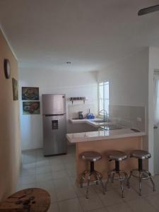 a kitchen with three bar stools and a stainless steel refrigerator at Comfortable and nice house in Caucel in Mérida
