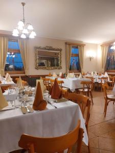 a restaurant with white tables and chairs and a mirror at Berki Vendéglő és Hotel in Körmend