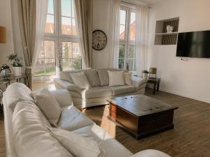 a living room with a white couch and a coffee table at "Unnen" in der Alten Schule Greetsiel in Krummhörn