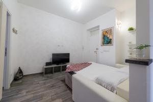 a white bedroom with a bed and a television at Di Giuseppe Laura in Ladispoli