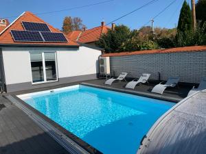 a swimming pool with three chairs and a house at Ady13 Vendégház Eger in Eger