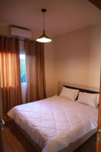 ein Schlafzimmer mit einem großen weißen Bett und einem Fenster in der Unterkunft Angela chalet in Kfar Roummâne