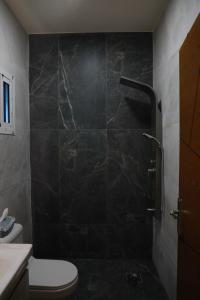 ein Badezimmer mit einer schwarz gefliesten Dusche mit Toilette in der Unterkunft Angela chalet in Kfar Roummâne + 7 Fotos
