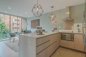 a kitchen with wooden cabinets and a large window at Luxury Studio El Poblado Pool Rooftop 4th Floor in Medellín