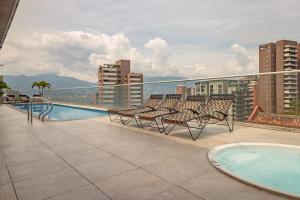 a balcony with chairs and a swimming pool on a building at Luxury Studio El Poblado Pool Rooftop 4th Floor in Medellín