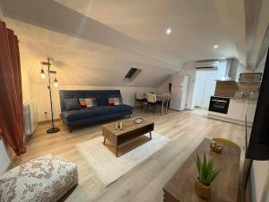 a living room with a blue couch and a table at Appartement douillet in Haspres