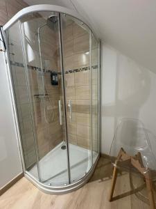 a glass shower in a room with a chair at Appartement douillet in Haspres