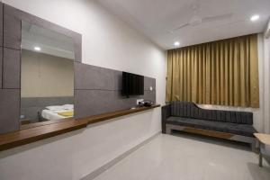 a hotel room with a couch and a mirror at StayGuru Hari Om Residency in Bhuj