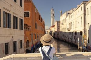 a person wearing a hat looking over a canal at Gabrielli Luxury Apartments Venezia - Starhotels Collezione in Venice