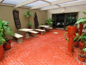 a patio with benches and potted plants on a brick floor at Ngandu at Sea in Meersig