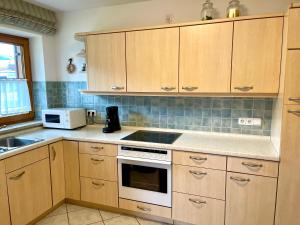 a kitchen with wooden cabinets and a white stove top oven at Ferienwohnung Alpenrose Sommer-Hörnerbahnen kostenlos in Obermaiselstein +10 photos