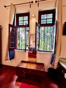 a living room with windows and a wooden bench at Colonial Boutique Villa Kandy in Kandy