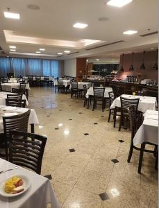 a dining room with tables and chairs with a plate of food at Hotel Sol Alphaville in Barueri