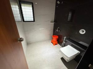 a bathroom with a white toilet and a orange bucket at Aanandi Resort in Shirdi