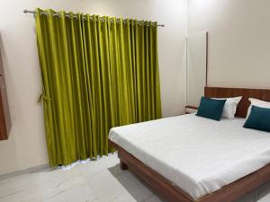 a bedroom with a bed with a green curtain at Aanandi Resort in Shirdi +16 photos