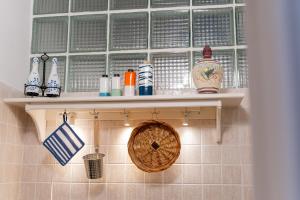 a shelf in a kitchen with bottles and a basket at Il Da Vinci Apartment in Giovinazzo