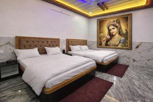 two beds in a room with a painting on the wall at Hotel Bhavishyaa Vrindavan in Vrindāvan