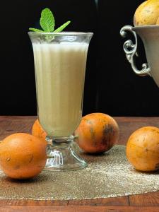 a glass of drink with a green leaf on top of oranges at Blackpool Farm House in Nuwara Eliya