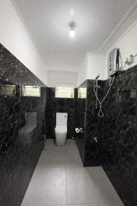a black bathroom with a toilet and a shower at Blackpool Farm House in Nuwara Eliya