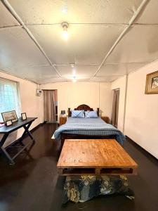 a bedroom with a bed and a wooden table at Blackpool Farm House in Nuwara Eliya