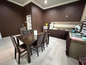 a dining room with a table and chairs in a kitchen at Villa Dr Din in Rantau Panjang