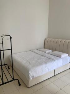 a bed in a bedroom with a white wall at De' Haven Stay - 10minutes to Airport Tawau in Tawau