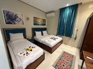 two beds in a room with blue curtains at Golden Palace Suites in Cairo