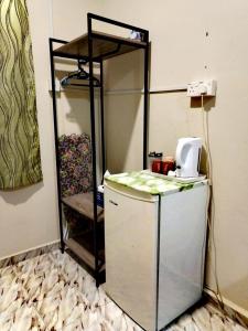 a small refrigerator in a room with a shelf at 4F Motel and Homestay by LTS in Pantai Cenang