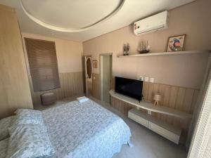 a bedroom with a bed and a flat screen tv at Casa riviera in Aquiraz