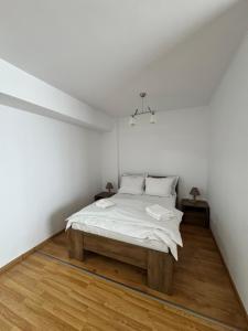 a white bedroom with a bed with a wooden floor at Class Belvedere Apartments in Oradea