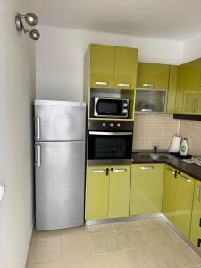 a kitchen with yellow cabinets and a stainless steel refrigerator at Class Belvedere Apartments in Oradea +21 photos