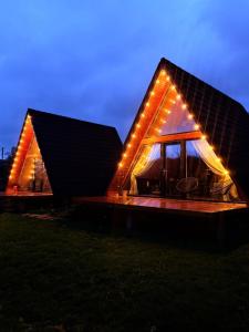 a house with lights on the front of it at night at MooN by Sun&Moon Cabins in Măneciu