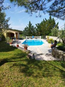 a pool in a yard with a person sitting next to it at Chambres d'hôtes Mas Lassagne in Vagnas