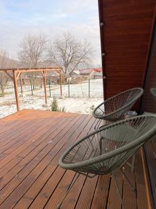 a wooden deck with two chairs on top of it at MooN by Sun&Moon Cabins in Măneciu
