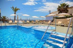 a swimming pool with a slide and chairs and umbrellas at Hotel Servigroup Koral Beach 4 Sup in Oropesa del Mar