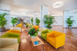a lobby with yellow and green chairs and plants at Hotel Servigroup Koral Beach 4 Sup in Oropesa del Mar +41 photos