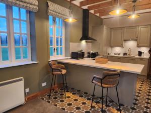 a kitchen with two bar stools and a counter at Recently refurbished former art studio in Rothiemay Station