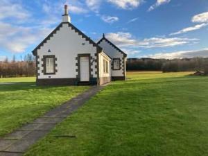 a small white church in a grassy field at Recently refurbished former art studio in Rothiemay Station