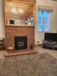 a living room with a brick fireplace and a television at Recently refurbished former art studio in Rothiemay Station