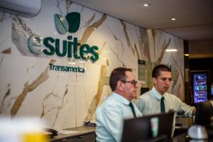 two men sitting at a desk with a laptop at Esuites Sorocaba in Sorocaba