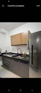 a kitchen with a stainless steel refrigerator and wooden cabinets at Apartamento Próximo Arena pantanal in Cuiabá