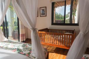 a bedroom with a crib and a bed with curtains at Kena Beach Villas in Marumbi +42 photos