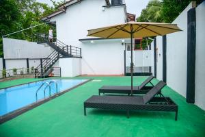 two chairs and an umbrella next to a swimming pool at Amila Resort - Habarana in Habarana