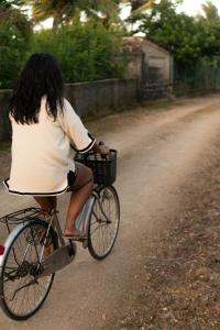 a woman riding a bike down a dirt road at Kena Beach Villas in Marumbi