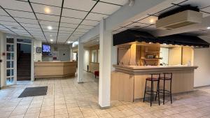 a lobby with a kitchen and a bar with stools at Mot Hotel in Claye-Souilly +6 photos