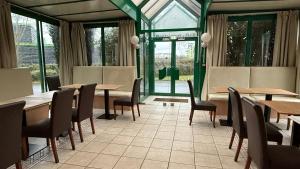 a restaurant with wooden tables and chairs and windows at Mot Hotel in Claye-Souilly