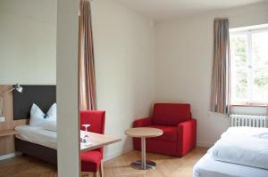 a hotel room with a bed and a red chair and a table at Hotel Landgut Burg in Weinstadt +32 photos