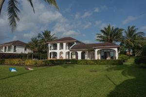 a large white house with palm trees and a yard at Kena Beach Villas in Marumbi